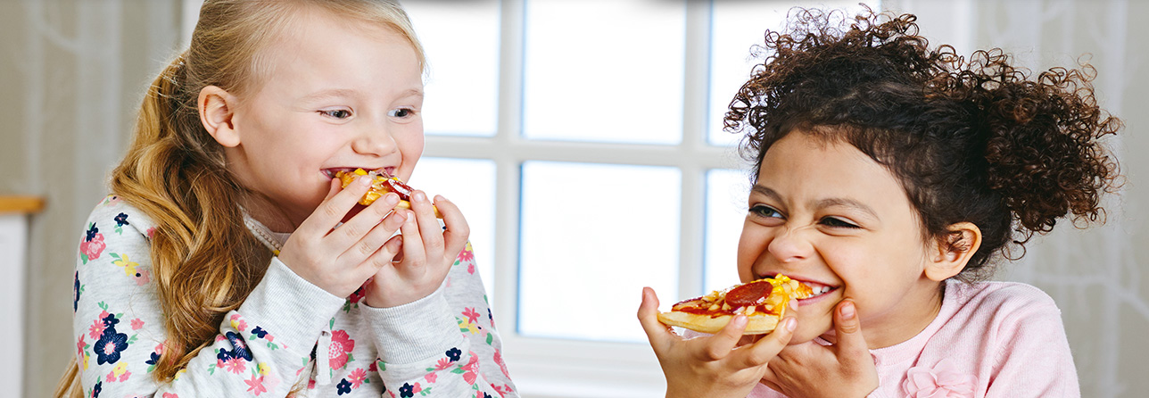 2 girls smiling and eating food